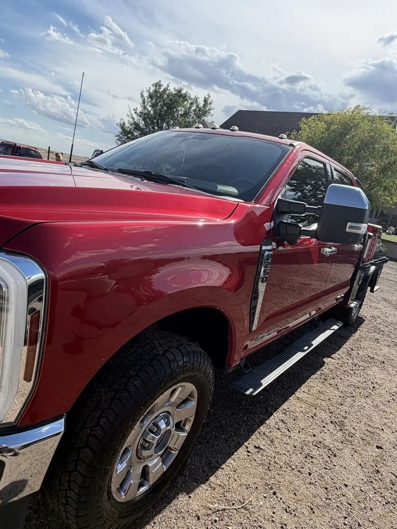Red Ford Super Duty work truck washed and detailed, parked on gravel