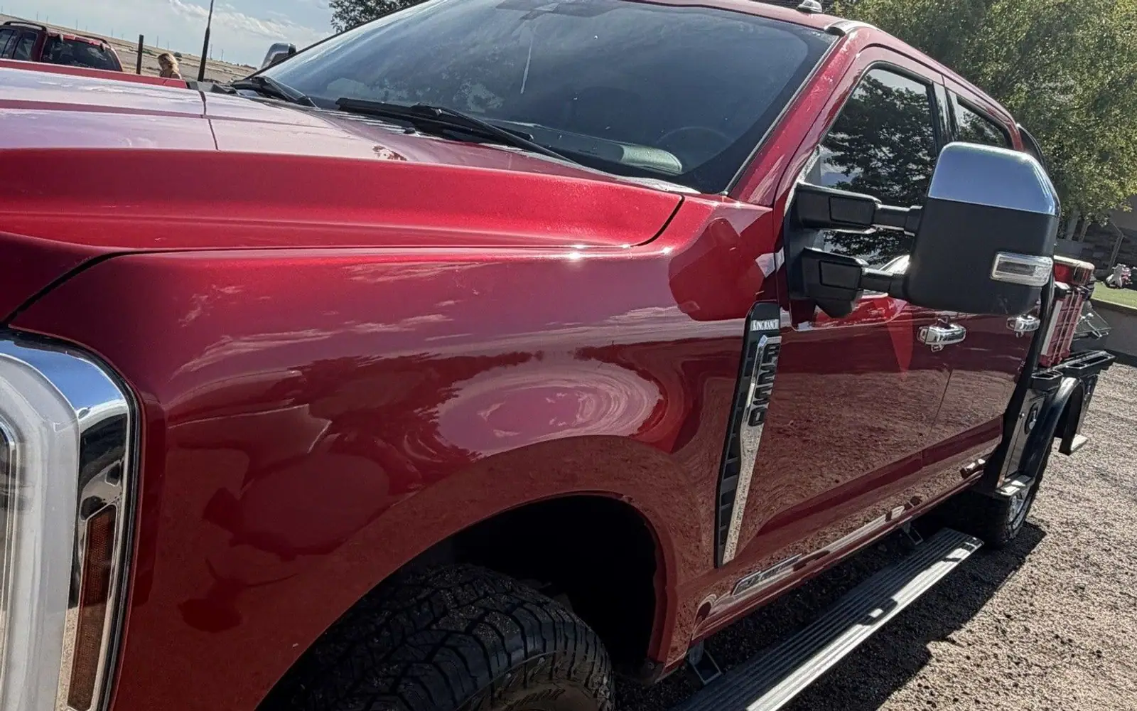 Red Ford Super Duty work truck washed and detailed, parked on gravel