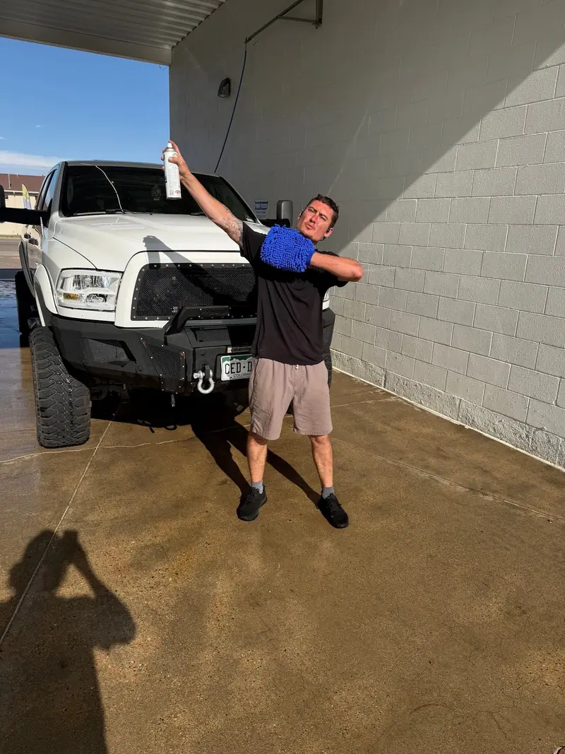 KJ of KJ Auto Detail with a wash mitt next to a white Ram pickup