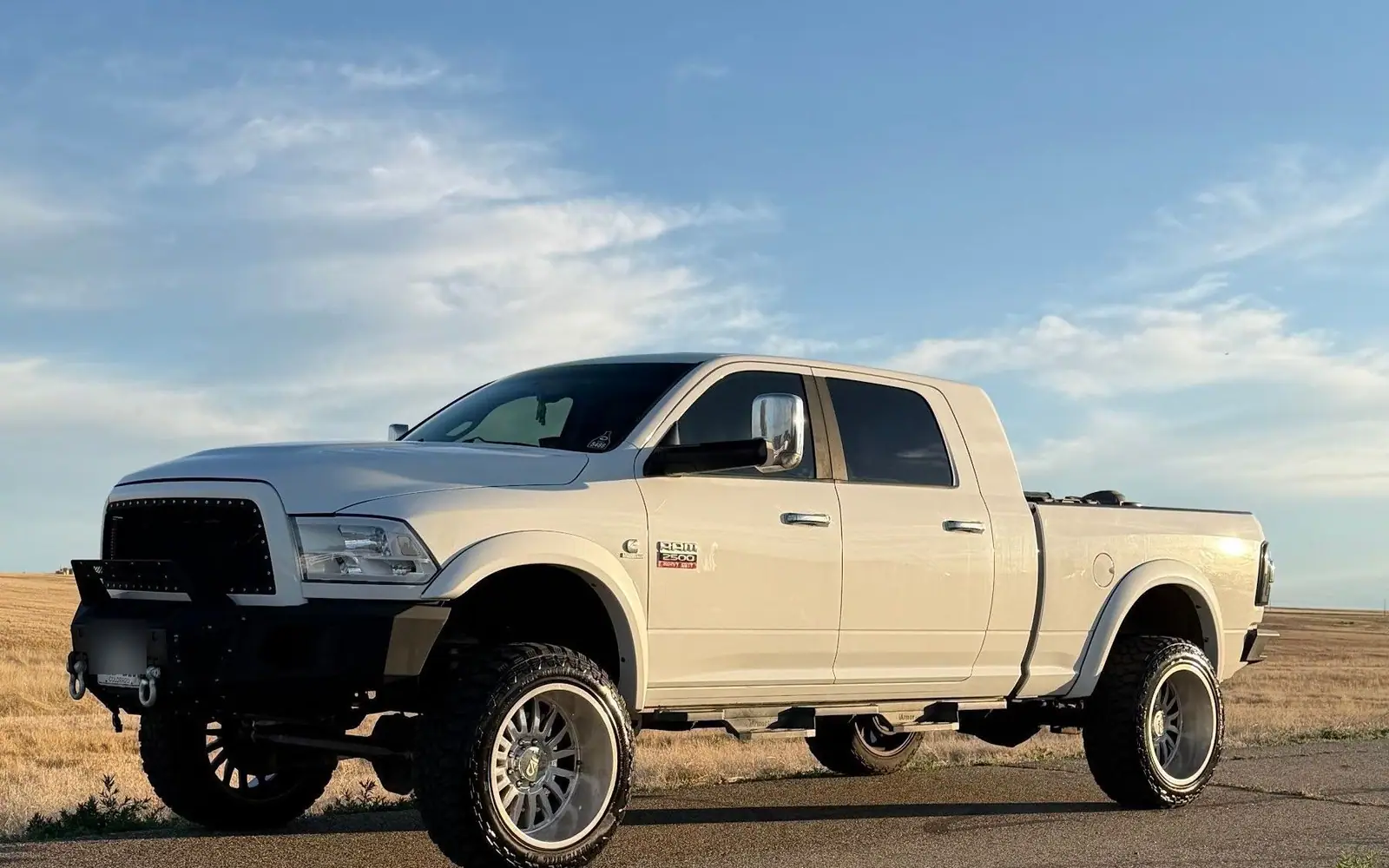 Detailed white Ram 2500 parked on the open plains of Weld County at golden hour