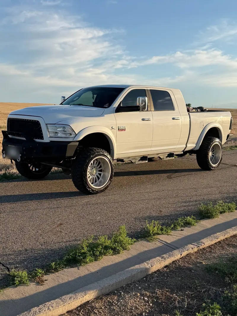 White lifted Ram 2500 Mega Cab, clean and gleaming on a gravel lot under a big Colorado sky