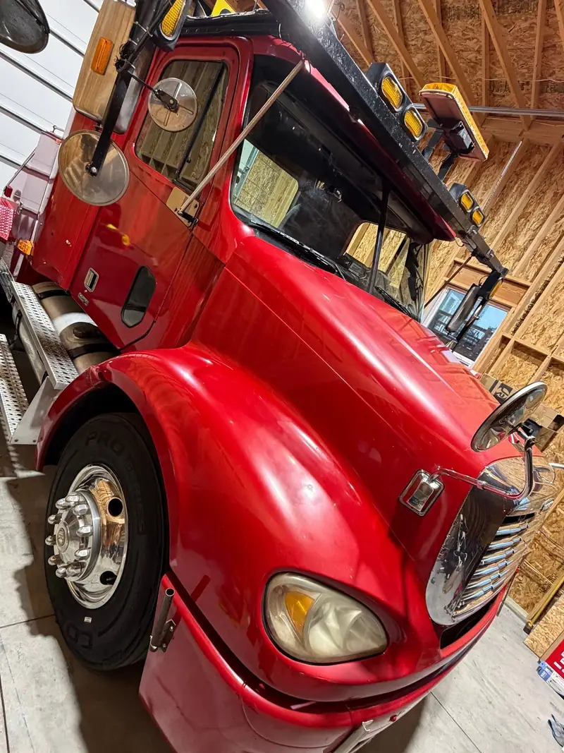 Red semi truck cab, freshly detailed, inside a timber shop building