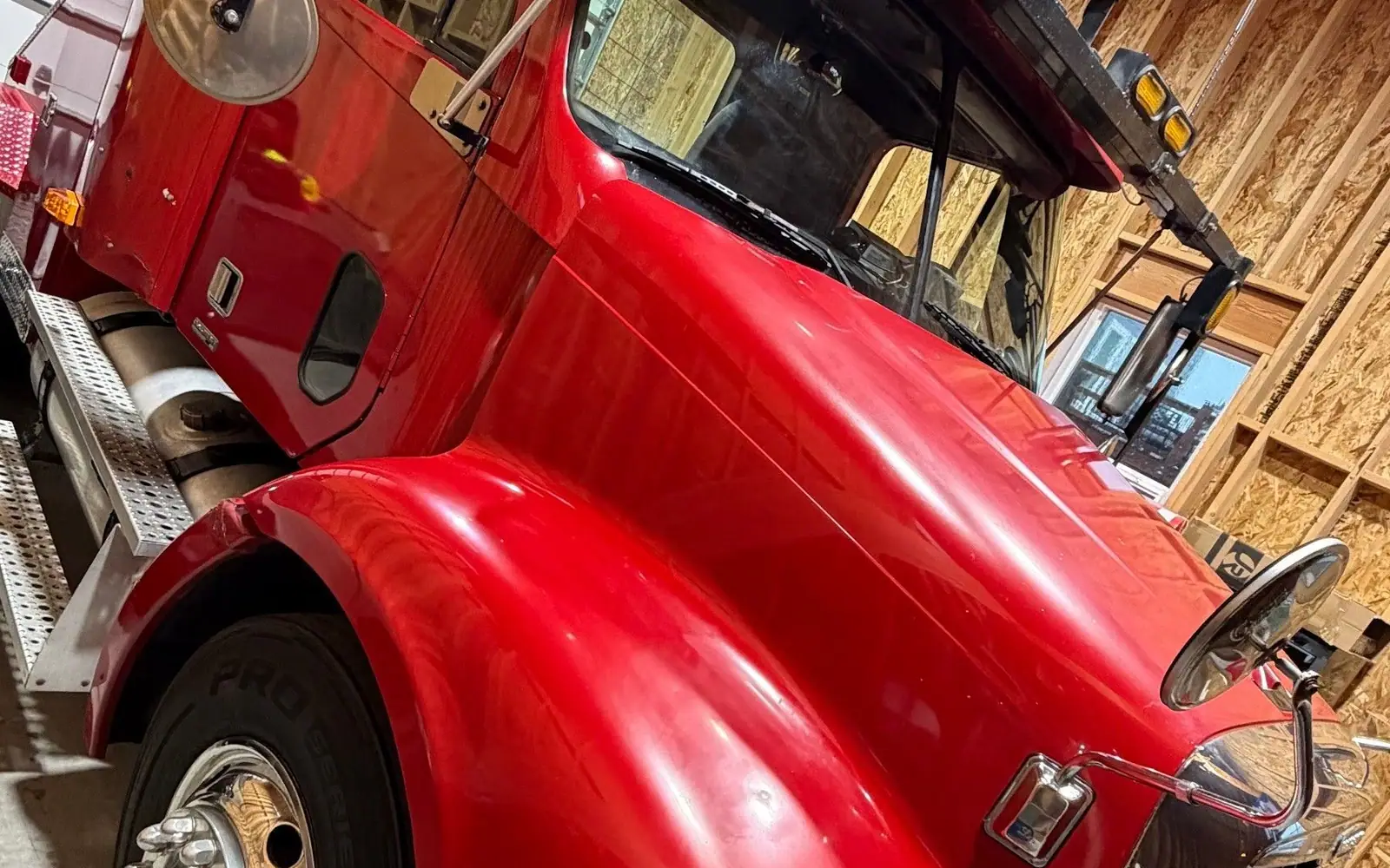 Red semi truck cab, freshly detailed, inside a timber shop building